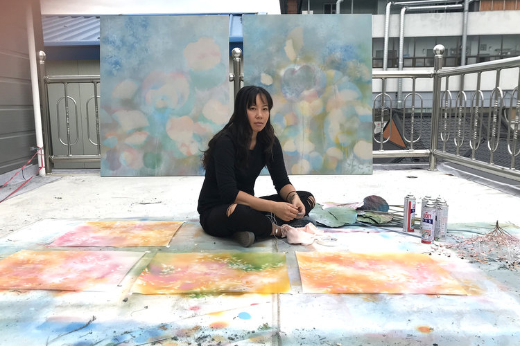 Artist Christine Nguyen sits cross-legged in her studio